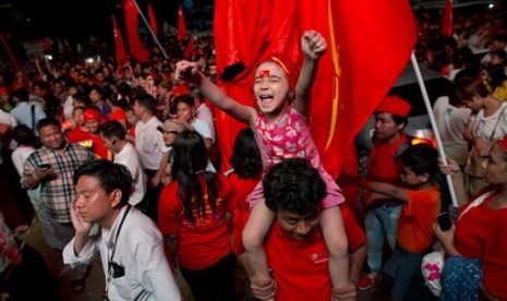 A child joins adult supporters of Myanmar's National League for Democracy party to celebrate as unofficial election results are posted outside the NLD headquarters in Yangon, Myanmar, Monday, Nov. 9, 2015. 