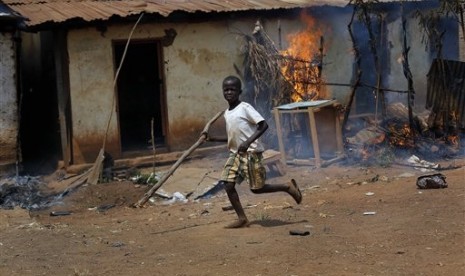 A child runs by a burning house as Anti-Balaka Christan youth loot the Muslim market in the PK13 district of Bangui, Central African Republic, Wednesday, Jan. 22, 2014.