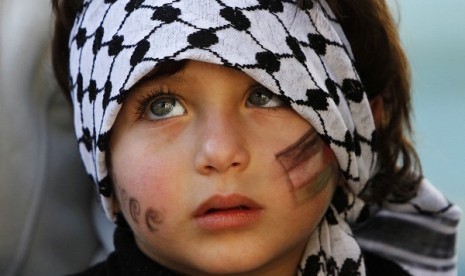 A child wears a keffiyeh headdress during a rally in the West Bank city of Ramallah, supporting the resolution that would change the Palestinian Authority's United Nations observer status from 