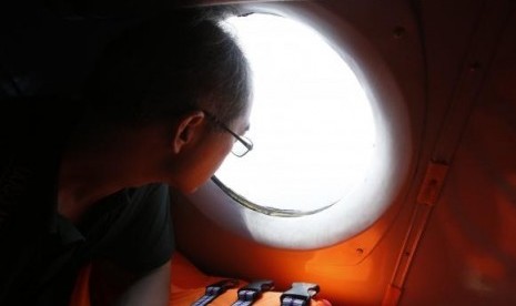 A Chinese journalist looks out from the window of a Vietnamese airforce AN-26 during a mission to find the missing Malaysia Airlines flight MH370 off Tho Chu islands March 11, 2014.