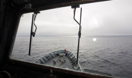 A crew member aboard the Australian Navy ship, HMAS Success, can be seen through a window looking for debris in the southern Indian Ocean during the search for missing Malaysia Airlines Flight MH370.