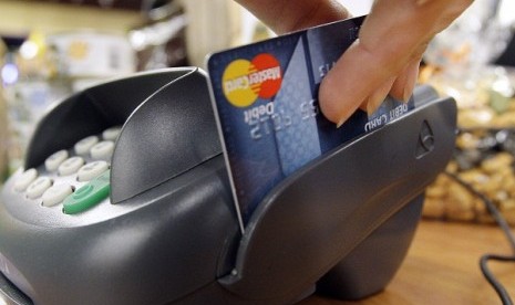 A customer runs a MasterCard debit card through a machine while checking-out at a shop. (illustration)