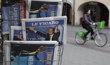 A cyclist rides past a news rack displying copies of French daily newspapers with front pages featuring France's newly-elected President in Strasbourg May 7, 2012, the day after Socialist party Francois Hollande won French presidency.   