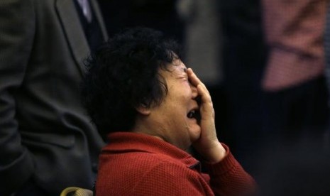 A family member of a passenger onboard Malaysia Airlines Flight MH370 covers her face as she cries after a routine briefing given by Malaysia Airlines in Beijing, March 22, 2014. 