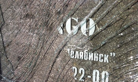 A fragment of a broken door glass, currently placed near an entrance to a fashion and clothes store, which was damaged by a shockwave from a meteorite, is seen in the centre of the Urals city of Chelyabinsk on Sunday.