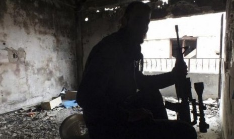 A Free Syrian Fighter holds his weapon inside a damaged building in the besieged area of Homs, January 4, 2014.