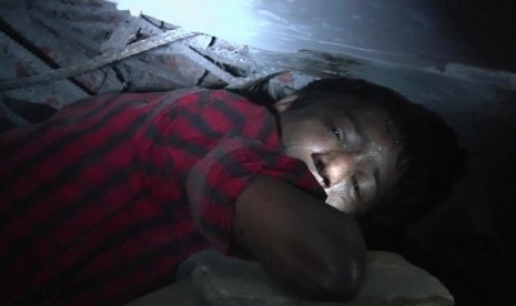 A garment worker Mohammad Altab moans to rescuers for help while trapped between concrete slabs and next to two corpses in a garment factory that collapsed Wednesday in Savar, near Dhaka, Bangladesh, Thursday, April 25, 2013. 