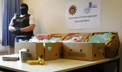 A German police officer poses next to a table laden with confiscated cocaine during a new conference in Berlin, January 7, 2014.