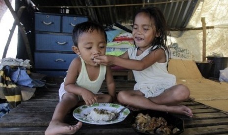 A girl feeds her brother inside a makeshift shelter for Typhoon Bopha victims in New Bataan, southern Philippines December 12, 2012. 