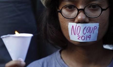 A girl holds a candle during a protest against military rule in central Bangkok, a day after Thai army chief seized power in a coup May 23, 2014. 