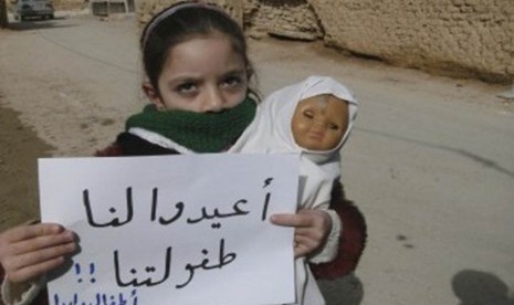 A girl holds a doll and a banner during a protest against Syria's President Bashar al-Assad in Daria, near Damascus, February 12, 2012. The banner reads: Bring back our childhood.