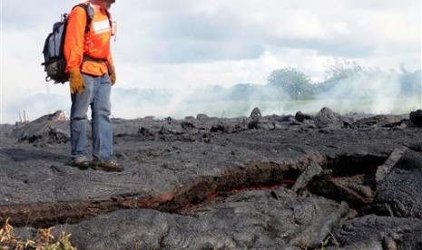 A Hawaii Volcano Observatory geologist standing on a partly cooled section of lava flow near the town of Pahoa on the Big Island of Hawaii on Oct 25, 2014.