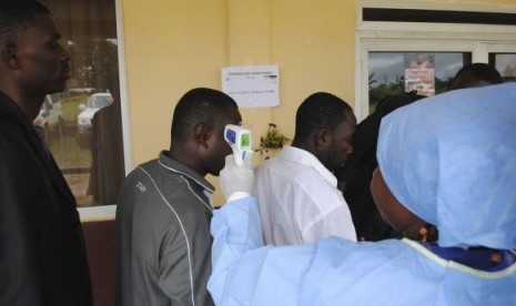 A health worker takes the temperature of people at a news conference on the opening of a new Ebola clinic, outside Monrovia October 3, 2014.