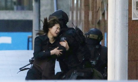 A hostage runs towards a police officer outside Lindt cafe, where other hostages are being held, in Martin Place in central Sydney December 15, 2014. 