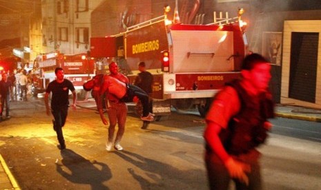 A man carries an injured man, victim of a fire at the Kiss club in Santa Maria city, Rio Grande do Sul state, Brazil, early Sunday, Jan. 27, 2013. 