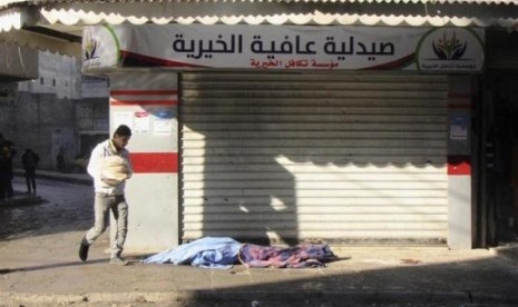 A man carrying bread walks past covered dead bodies lying on the ground after what activists said was an air raid by forces loyal to Syrian President Bashar Al-Assad, at Masaken Hanano in Aleppo, December 22, 2013.