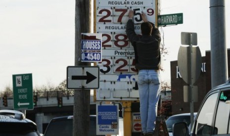 A man changes the price for a gallon of gasoline at a gas station in Medford, Massachusetts December 4, 2014. 