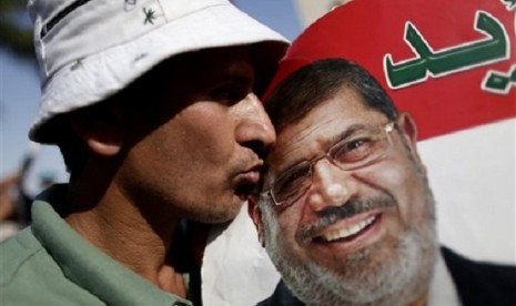 A man kisses a poster with the photograph of Egypt's Islamist President Mohammed Mursi during a rally, in Nasser City, Cairo, Egypt, Wednesday, July 3, 2013. 