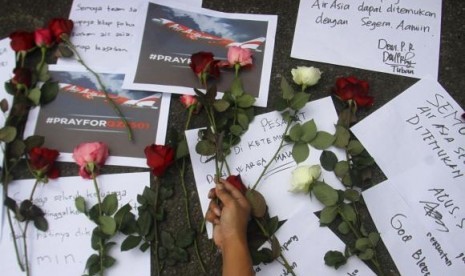 A man places flowers down as a sign of respect to Air Asia QZ 8501 passengers in Batu, East Java province, December 30, 2014