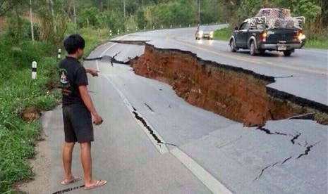 A man points a big crack on a damaged road following a strong earthquake in Phan district of Chiang Rai province, northern Thailand, Monday, May 5, 2014. 