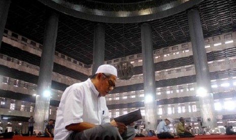 A man recites Quran after noon praying at Istiqlal.   