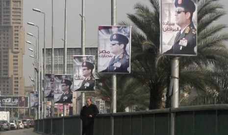 A man stands on a bridge where huge posters of Egypt's Army chief Field Marshal Abdel Fattah al-Sisi are hanged in central Cairo February 3, 2014.