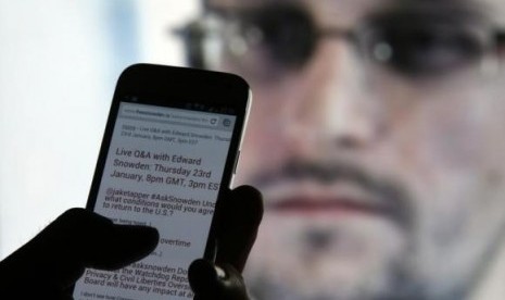 A man uses his cell phone to read updates about former US spy agency contractor Edward Snowden answering users' questions on Twitter in this photo illustration, in Sarajevo, January 23, 2014.