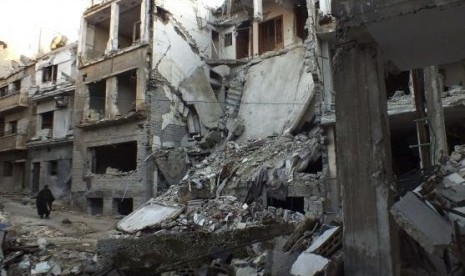 A man walks along a street lined with damaged buildings in the besieged area of Homs February 5, 2014.