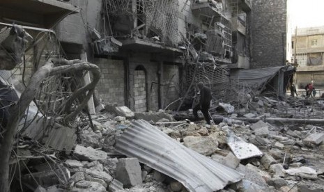 A man walks amid rubble of damaged buildings in the al-Myassar neighbourhood of Aleppo February 19, 2014.