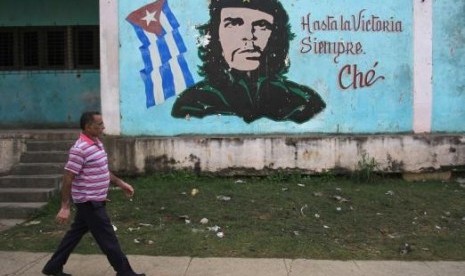 Seorang pria berjalan melewati lukisan pahlawan revolusi Ernesto 'Che' Guevara di Havana, Kuba.