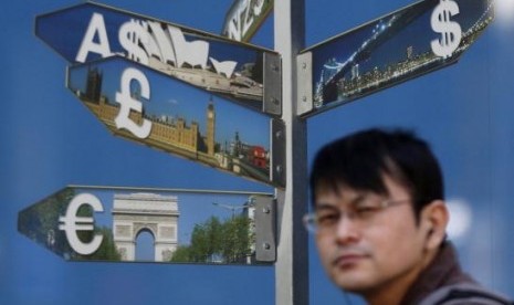 A man walks past various currency signs, including the dollar (top Right), Australian dollar (top Left), pound sterling (centre L) and euro (bottom Left), outside a brokerage in Tokyo October 28 2014.