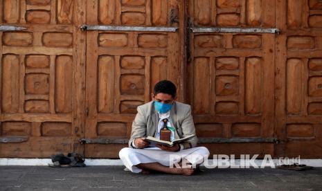 Apakah Diam Sebentar di Masjid Bisa Disebut Itikaf? Seorang pria mengenakan masker membaca Alquran di sebuah masjid di Ibu Kota Sana’a, Yaman.