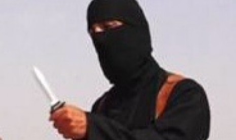 A masked Islamic State militant holding a knife speaks next to man purported to be US journalist James Foley at an unknown location in this still image from an undated video posted on a social media website.