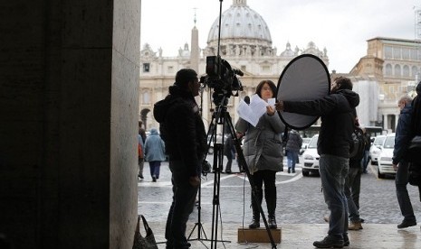 A media correspondent gives her report in Rome, as Saint Peter's Basilica at the Vatican is seen in the background February 11, 2013. 