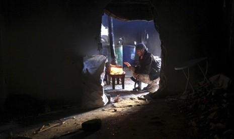 A member of opposition group warms himself around a fire as he is seen through a wall opening in Deir al-Zor, eastern Syria, December 12, 2013. (illustration)