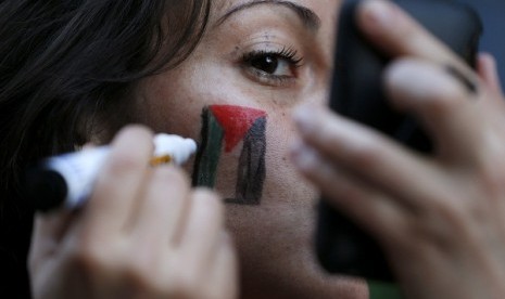 A supporter of Palestine draw Palestinian's flag on her cheek.