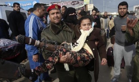 A member of the Palestinian security forces carries a girl, who needs to receive medical treatment outside Gaza, as she waits to cross into Egypt at the Rafah crossing between Egypt and the southern Gaza Strip December 21, 2014. 