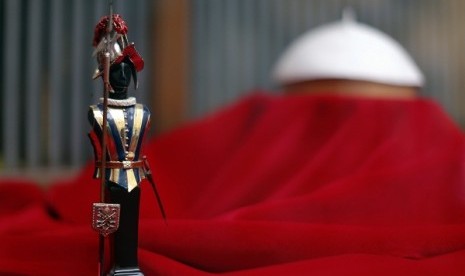 A model of a Swiss guard is seen next to a Papal white skull cap in the Gammarelli's tailor shop window in Rome March 8, 2013. Roman Catholic cardinals will vote later on Friday on when to start a conclave to elect a successor to Pope Benedict.