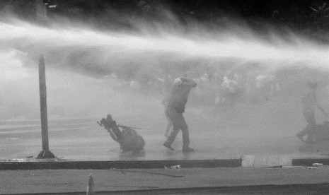 A news cameraman (left) falls on the ground as Turkish riot police spray water cannon at demonstrators in city's main Kizilay Square in Ankara, Turkey, Sunday, June 16, 2013. 