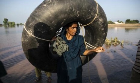 A Pakistani woman carries a rubber ring as she stands beside a flooded field following heavy rain in Cheniot, Punjab Province September 9, 2014.