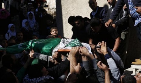 A Palestinian boy looks as mourners carry the body of 27-year-old Abdallah Shalaldeh, during his funeral in the West Bank village of Sa'ir, near Hebron, Thursday, Nov. 12, 2015