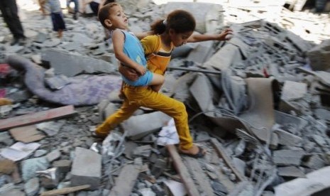 A Palestinian girl carries a child across rubble from a building that police said was destroyed by an Israeli air strike, in the Burij refugee camp in the central Gaza Strip August 1, 2014.