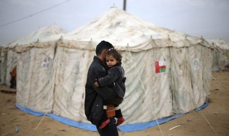 A Palestinian man carries his sister near tents erected by Palestinians whose houses were destroyed by what witnesses said was Israel shelling during a 50-day conflict last summer, east of Khan Younis in the southern Gaza Strip January 27, 2015. The main U