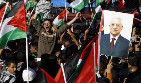 A Palestinian man cheers near a placard depicting President Mahmoud Abbas during a rally marking the U.N. General Assembly's upgrading of the Palestinians' status from 