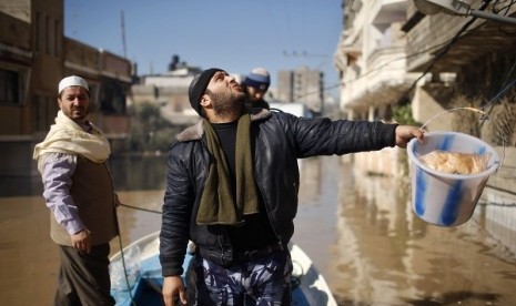 A Palestinian policeman carries a bucket containing food supplies, to be passed to people whose homes were flooded with rainwater, in the northern Gaza Strip December 15, 2013. 