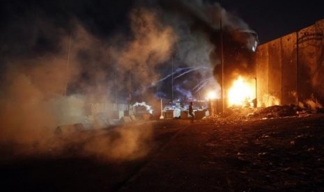 A Palestinian protester throws a stone toward Israeli troops as they fire tear gas during clashes at a protest against Israeli air strikes on Gaza, at Qalandia checkpoint near the West Bank city of Ramallah July 11, 2014.