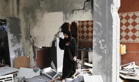 A Palestinian woman looks through her damaged home after returning to Beit Hanoun town, which witnesses said was heavily hit by Israeli shelling and air strikes during the Israeli offensive, in the northern Gaza Strip August 5, 2014.