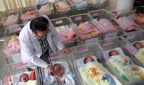 A pediatrician examines his patients in neonatal ward. (illustration)