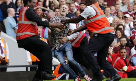 A pitch invader is restrained after taking a Tottenham Hotspur freekick during their English Premier League soccer match against West Ham United at Upton Park in London August 16, 2014