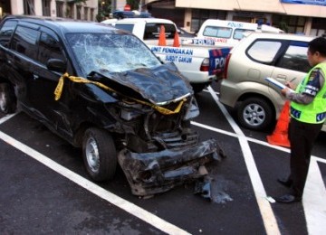 A police officer investigates the car involved in deadly crash in Jakarta. 